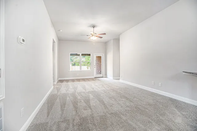 an empty room with windows and ceiling fan