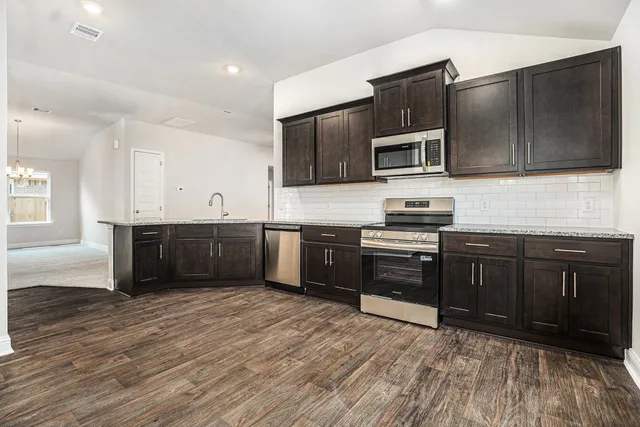 a kitchen with stainless steel appliances kitchen island granite countertop a stove a sink and a microwave