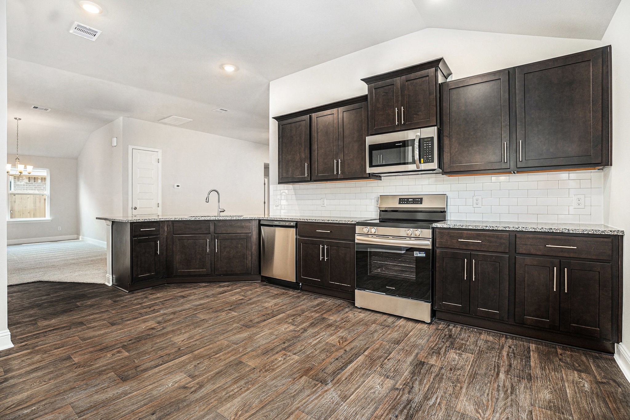 424 Bryan Street Angleton, TX 77515 - Photo 7 of 17 a kitchen with stainless steel appliances kitchen island granite countertop a stove a sink and a microwave