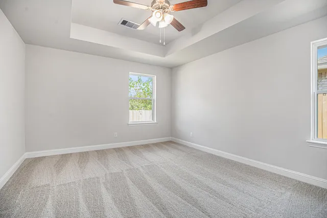 an empty room with a window and a ceiling fan