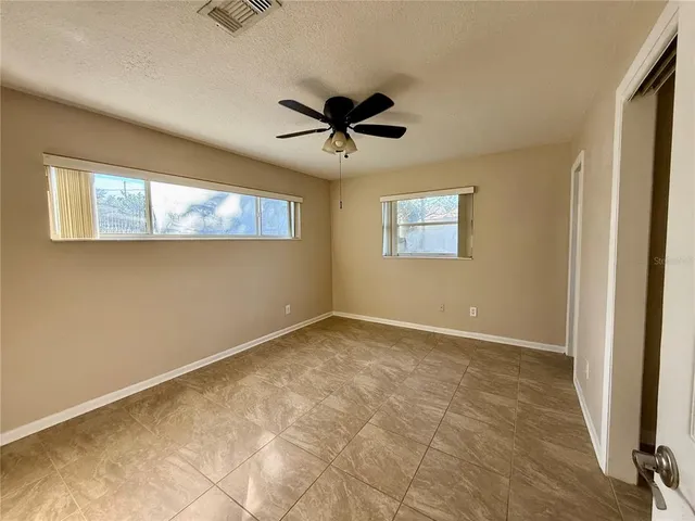 an empty room with windows and fan