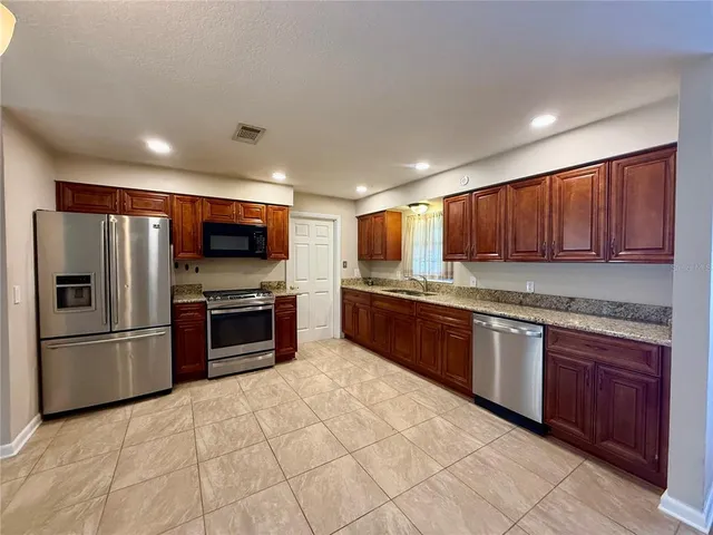 a kitchen with stainless steel appliances granite countertop a refrigerator and a stove top oven