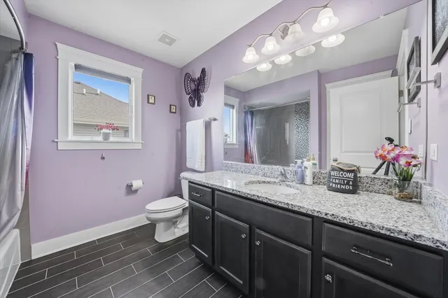 a bathroom with a granite countertop toilet sink and mirror
