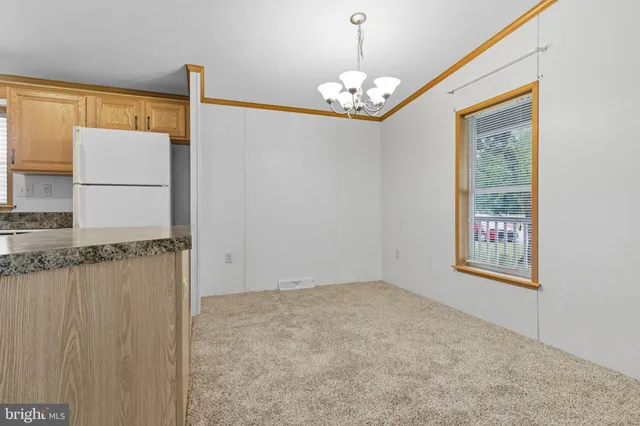 a view of an empty room with chandelier fan and fire place