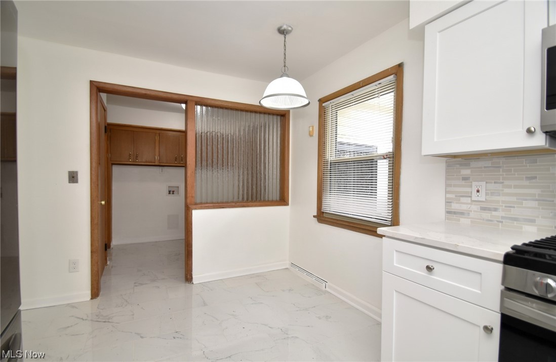 3681 Brinkmore Road Cleveland Heights, OH 44121 - Photo 13 of 27 Kitchen featuring light stone counters, light tile flooring, hanging light fixtures, white cabinetry, and backsplash