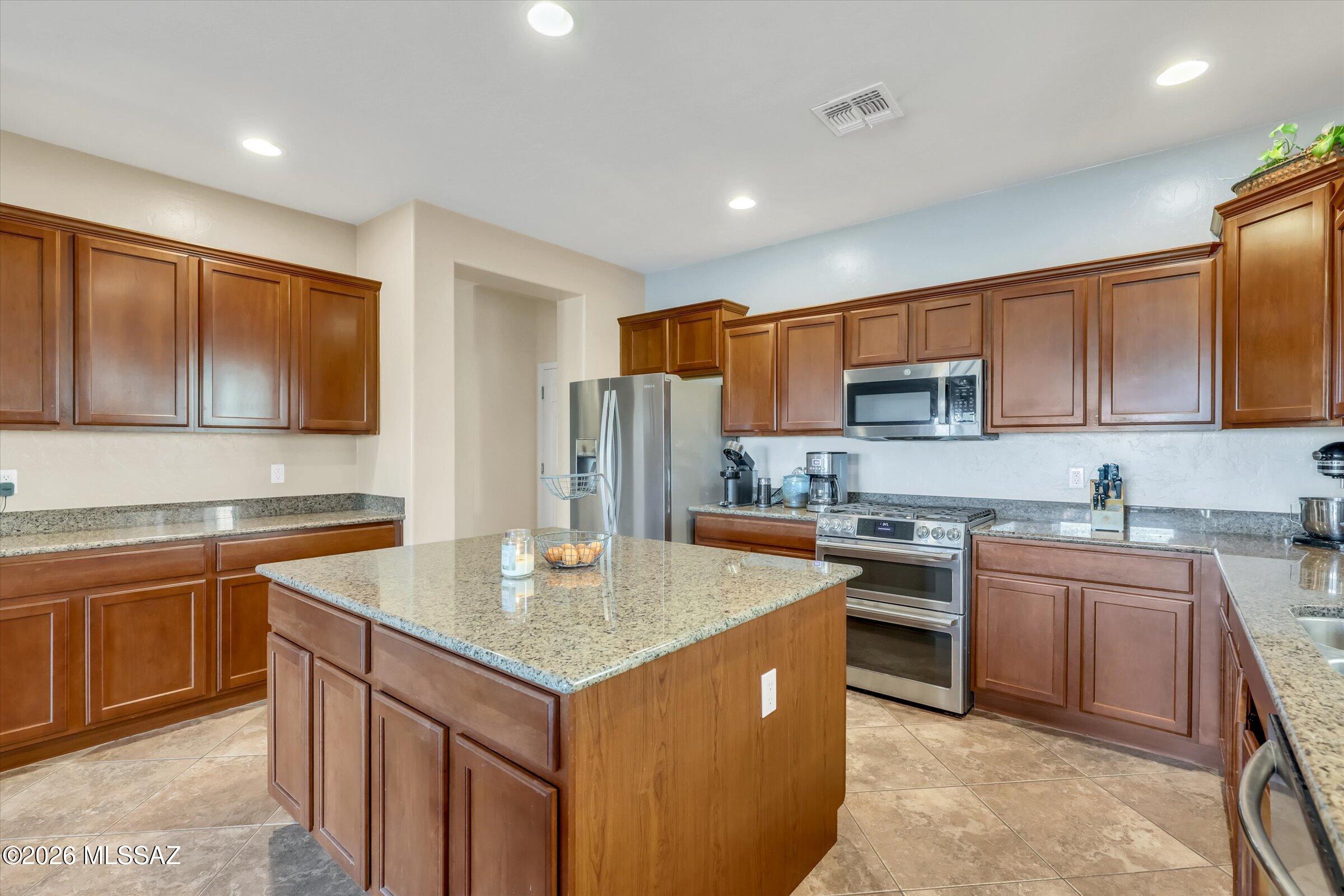 6095 South Jakemp Trail Tucson, AZ 85747 - Photo 20 of 52 a kitchen with stainless steel appliances granite countertop a sink stove microwave and refrigerator