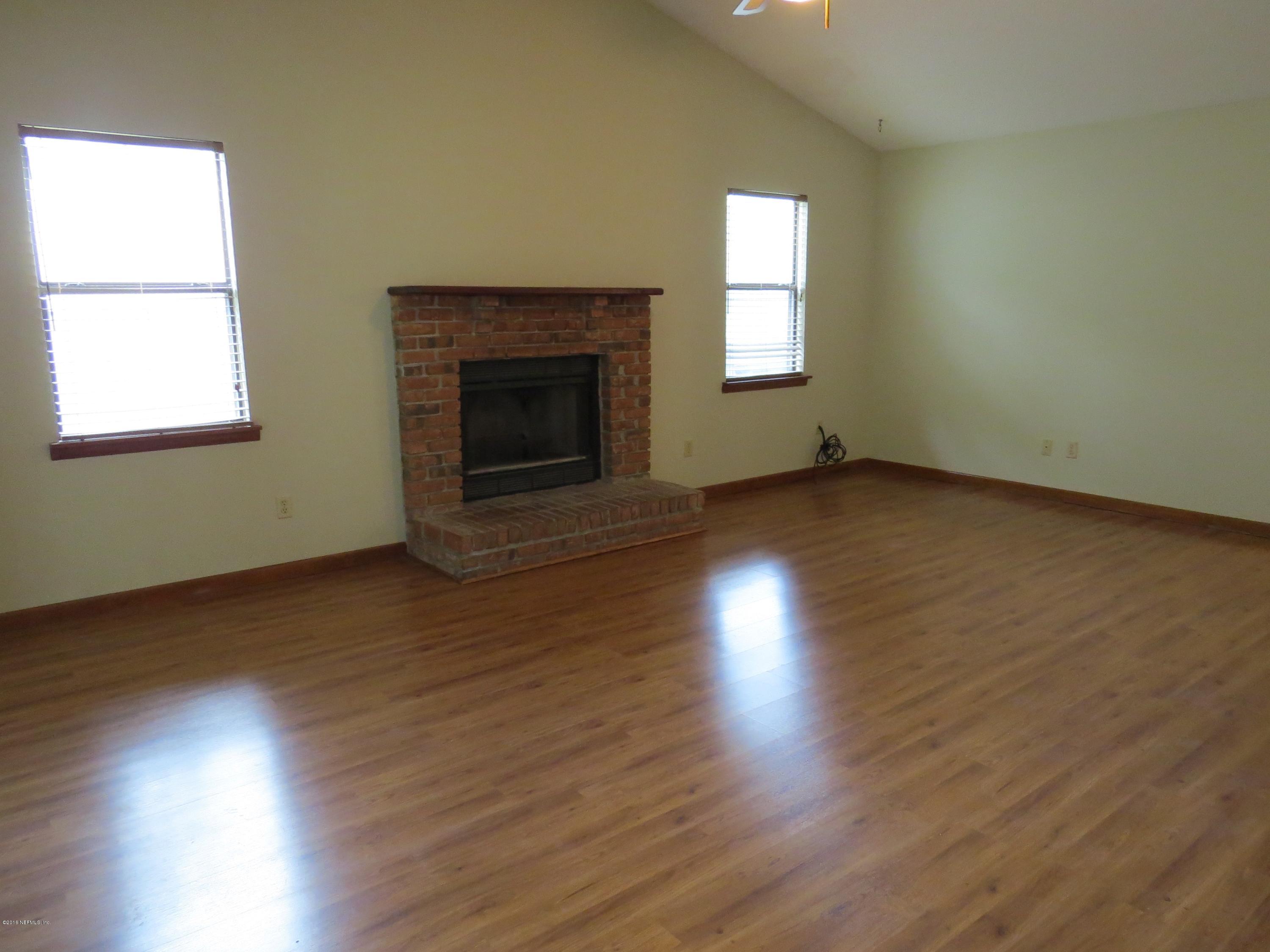 12770 Beaubien Road Jacksonville, FL 32258 - Photo 11 of 46 an empty room with wooden floor a fireplace and windows
