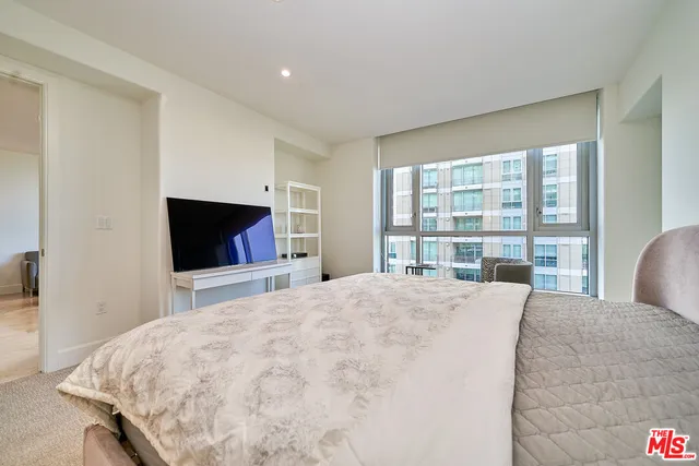 a large bedroom with a bed and a flat screen tv