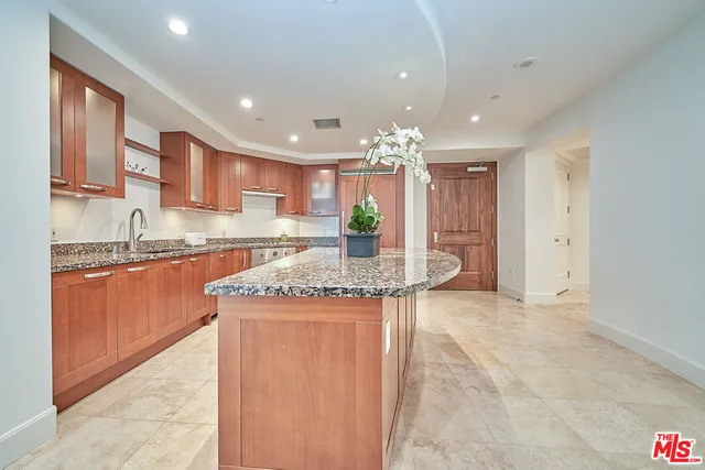 a kitchen with kitchen island granite countertop a sink and cabinets