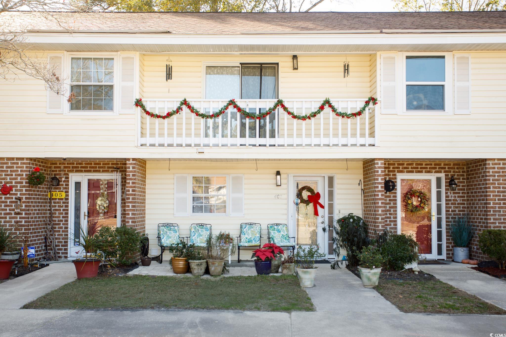 Colonial inspired home featuring a balcony, brick siding, and roof with shingles