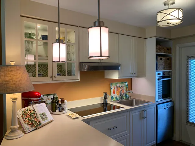 a kitchen with stainless steel appliances granite countertop a sink dishwasher and a flat tv screen next to a window