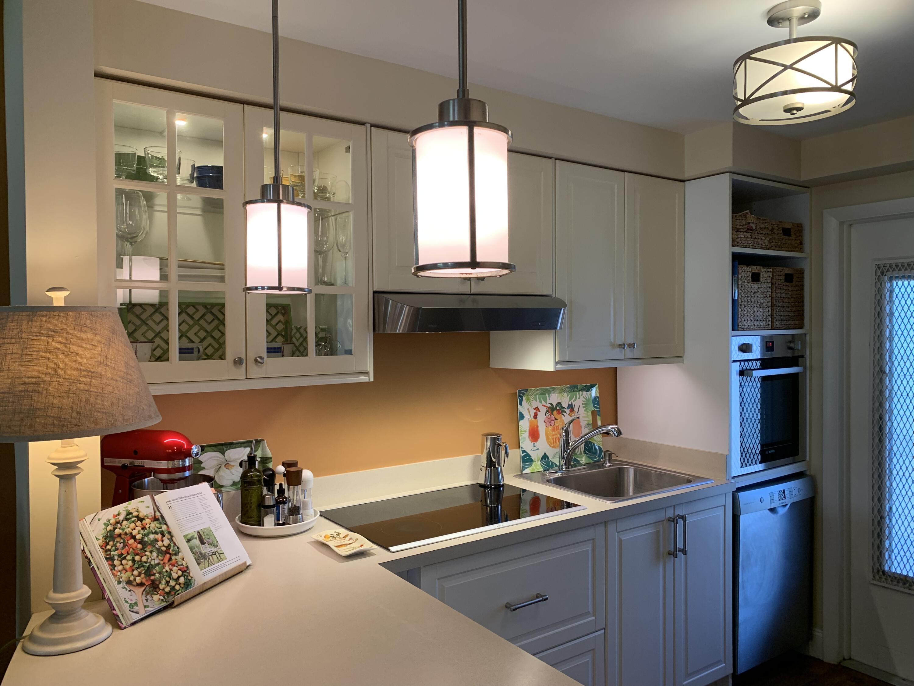 1951 Northeast 39th Street Northeast, Unit 249 Lighthouse Point, FL 33064 - Photo 7 of 23 a kitchen with stainless steel appliances granite countertop a sink dishwasher and a flat tv screen next to a window