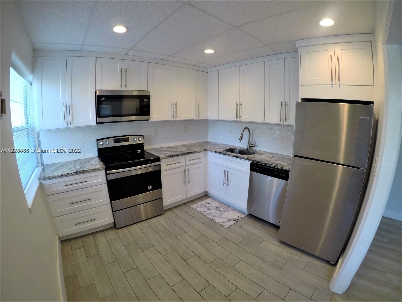 8927 Harding Avenue Surfside, FL 33154 - Photo 13 of 22 a kitchen with stainless steel appliances granite countertop a refrigerator stove a sink and a microwave