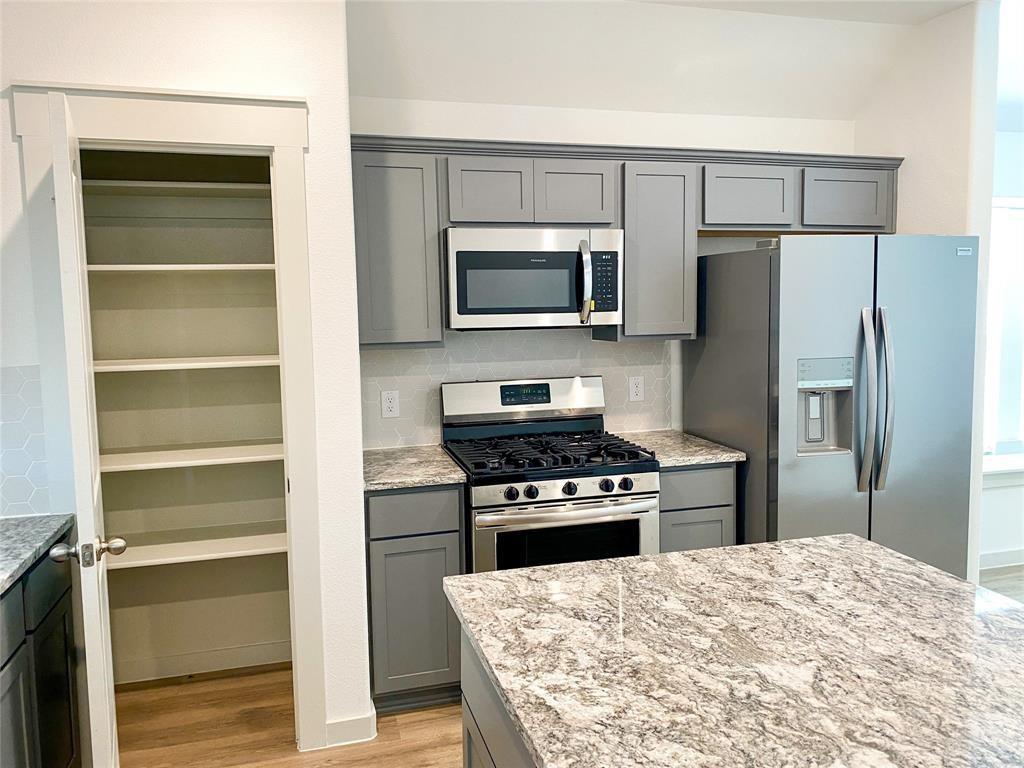 1372 Cedar Street Forney, TX 75126 - Photo 6 of 13 Kitchen with gray cabinets, stainless steel appliances, and backsplash