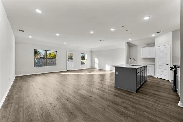 a view of kitchen with stainless steel appliances granite countertop a large counter top a stove and a wooden floors