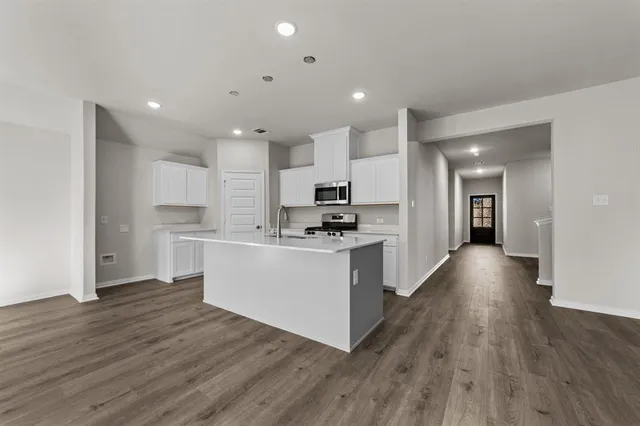 a view of kitchen with cabinets stainless steel appliances and wooden floor