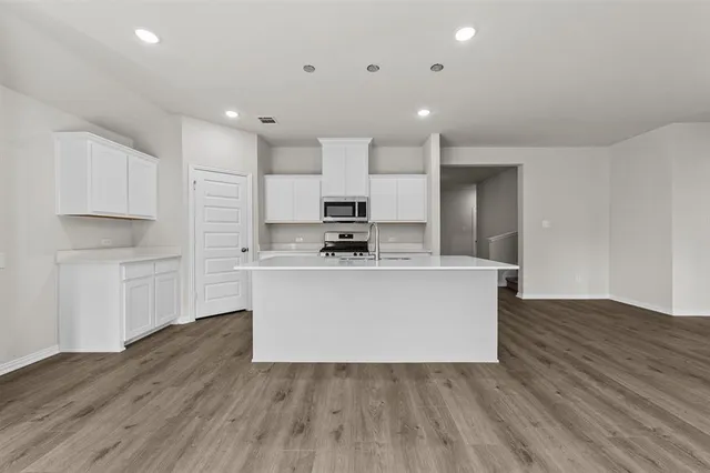a view living room with stainless steel appliances kitchen island sink and wooden floor