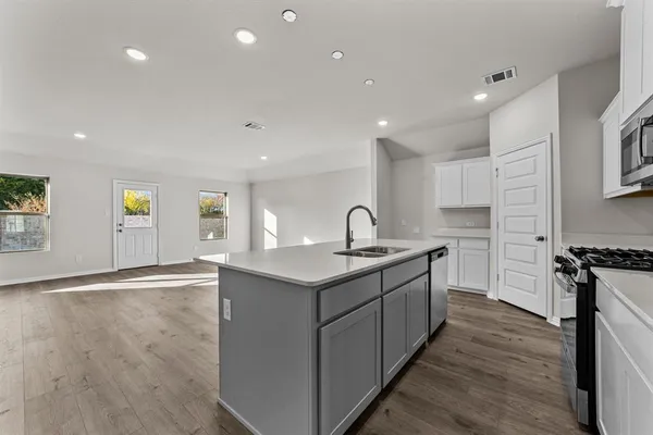 a kitchen with stainless steel appliances granite countertop a sink a stove and a wooden floors