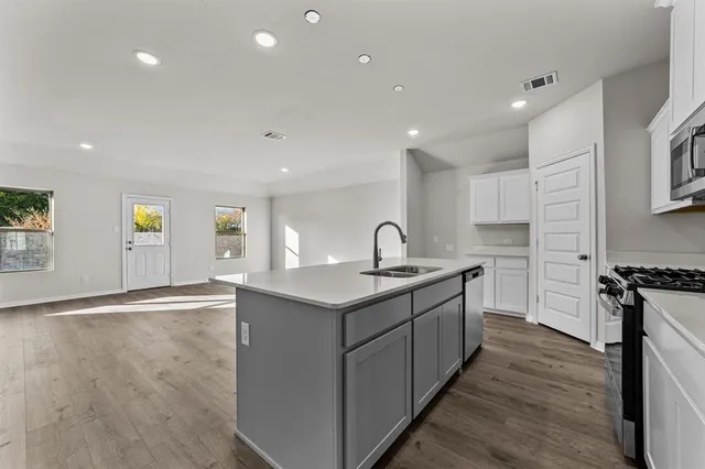 a kitchen with stainless steel appliances granite countertop a sink a stove and a wooden floors