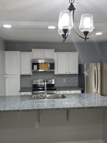 a kitchen with stainless steel appliances granite countertop a sink a stove and a microwave