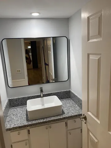 a en suite bathroom with a granite countertop sink and a mirror