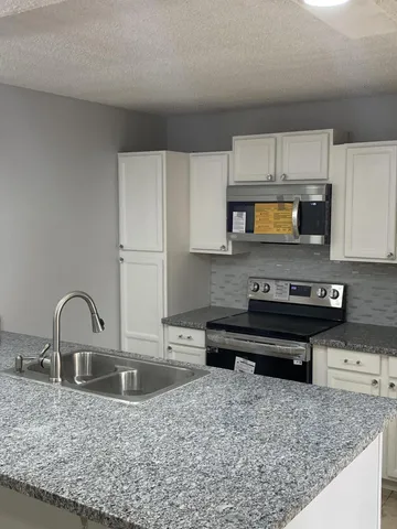 a kitchen with stainless steel appliances granite countertop a sink a stove and a microwave