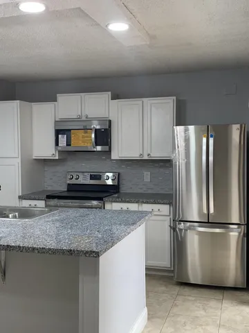a kitchen with granite countertop a refrigerator and a sink