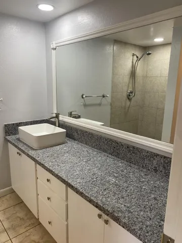 a bathroom with a granite countertop sink and shower