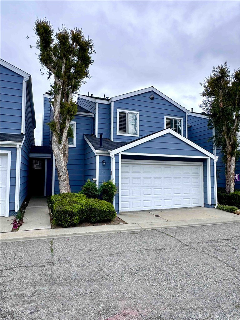 14152 Foothill Boulevard, Unit 35 Sylmar, CA 91342 - Photo 2 of 30 a front view of a house with a yard and garage
