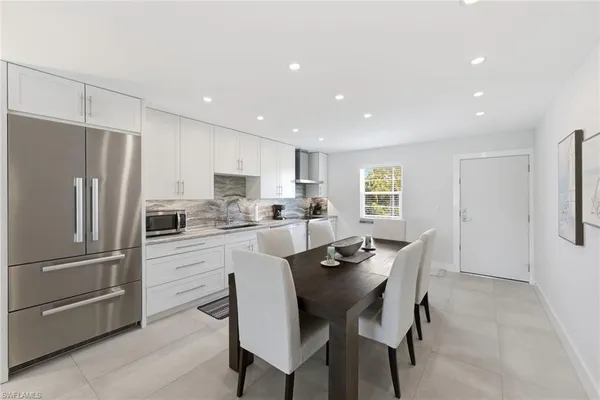 a kitchen with a refrigerator a dining table and chairs