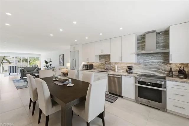 a kitchen with stainless steel appliances kitchen island granite countertop a stove a sink a refrigerator dining table and chairs