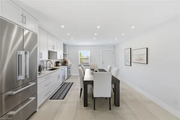 a white kitchen with wooden floor and stainless steel appliances