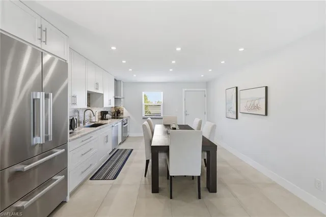 a white kitchen with wooden floor and stainless steel appliances