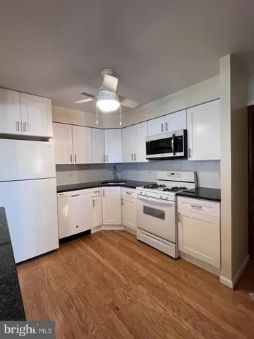 a kitchen with granite countertop white cabinets and white appliances