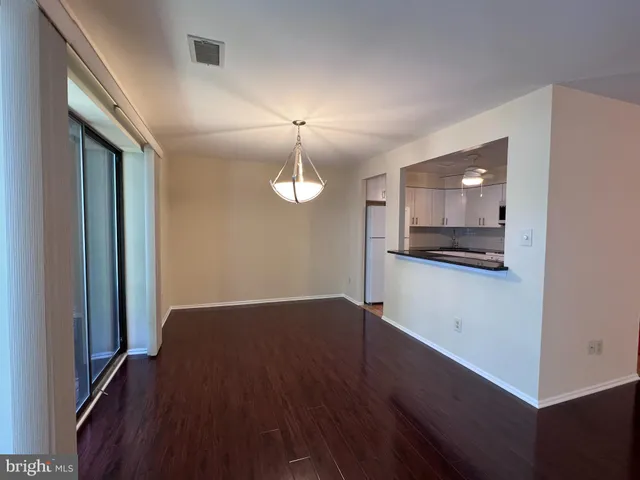an empty room with wooden floor mirror and windows