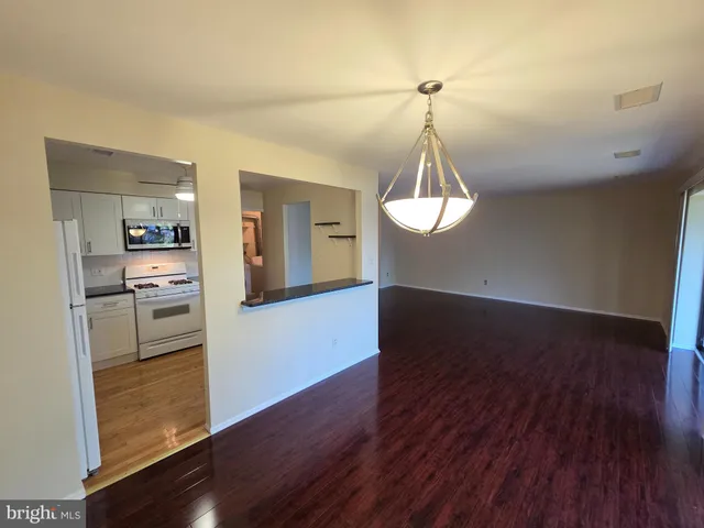 a view of a kitchen with wooden floor electronic appliances and cabinets