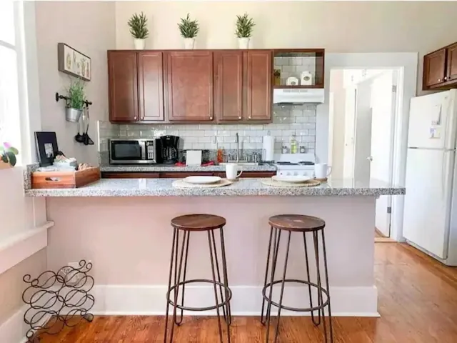 a kitchen with stainless steel appliances kitchen island granite countertop a table chairs sink and cabinets