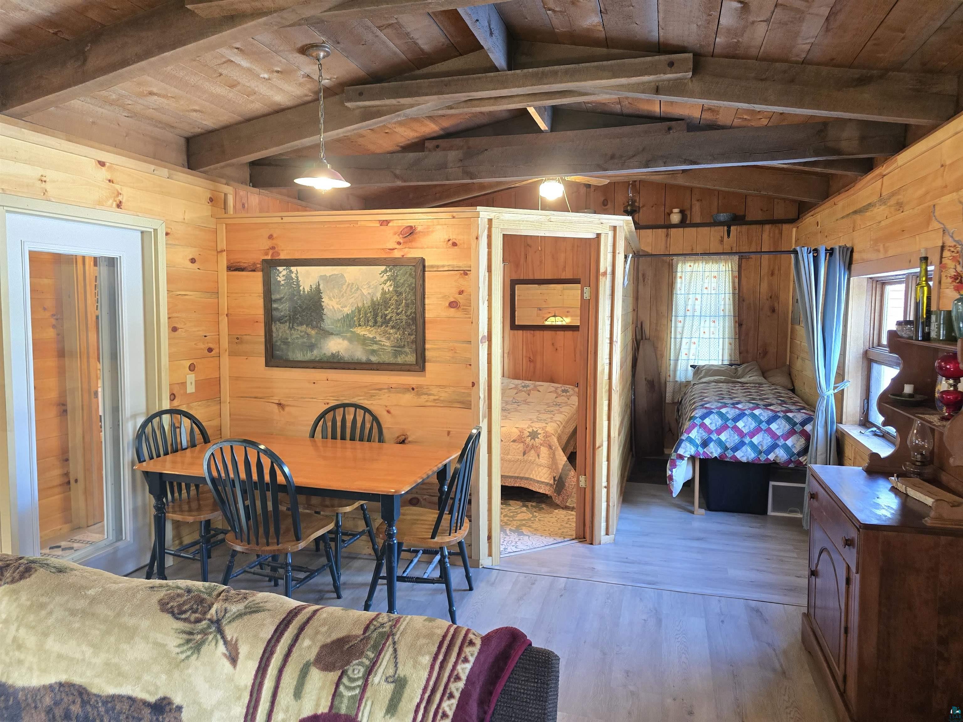 88910 Bark Point Road Herbster, WI 54844 - Photo 14 of 31 Dining room with wooden ceiling, vaulted ceiling with beams, wooden walls, and wood finished floors