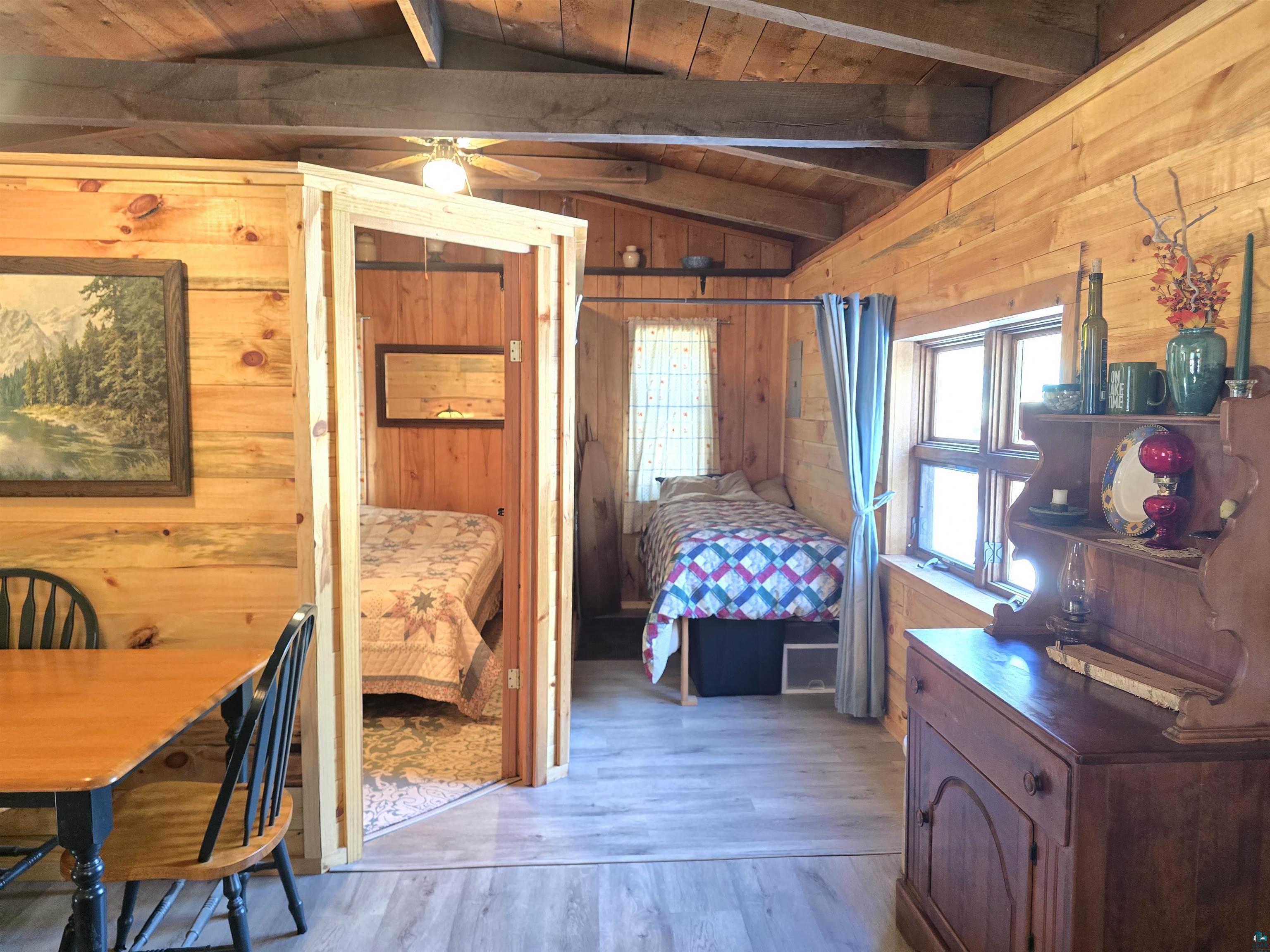 88910 Bark Point Road Herbster, WI 54844 - Photo 19 of 31 Bedroom featuring vaulted ceiling with beams, wooden ceiling, wood finished floors, and wooden walls