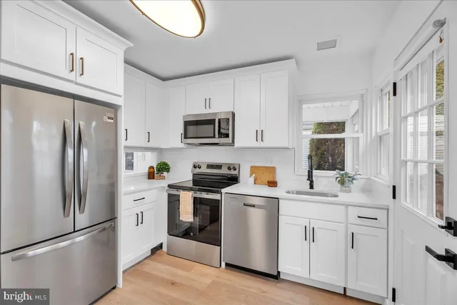 a kitchen with white cabinets stainless steel appliances and a window