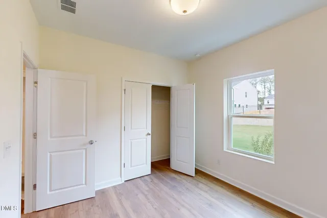 a view of an empty room with closet and a window