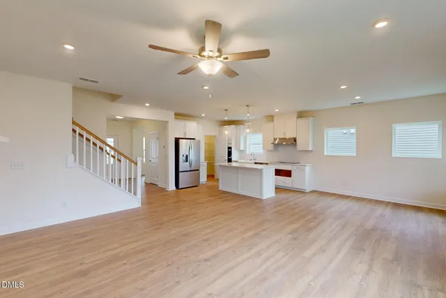 a view of a kitchen with a sink stainless steel appliances wooden floor and a window