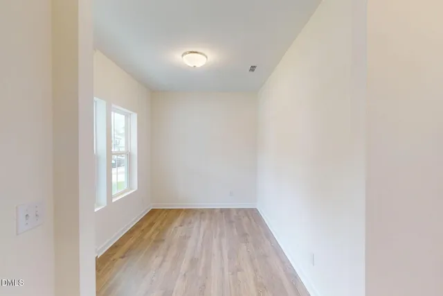 a view of a room that has wooden floor and window