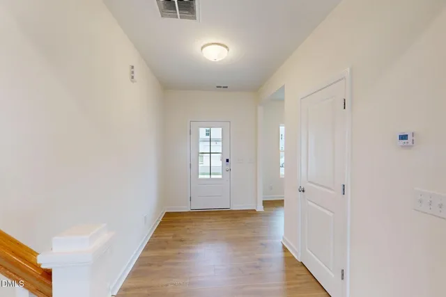 a view of a hallway with wooden floor and a bathroom
