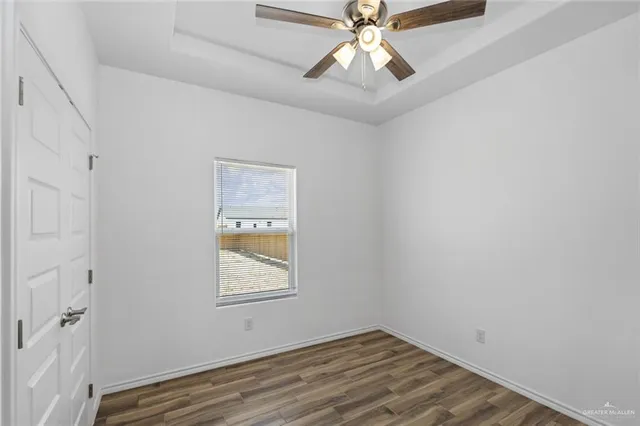 a view of an empty room with a window and wooden floor