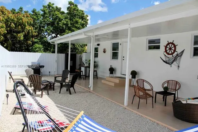 a view of a dining room and livingroom with furniture wooden floor a rug a flat screen tv a rug and a chandelier