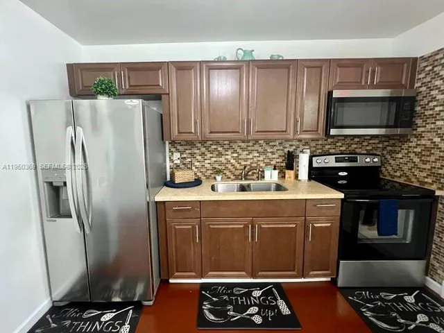 a kitchen with stainless steel appliances a refrigerator a stove a sink and a oven