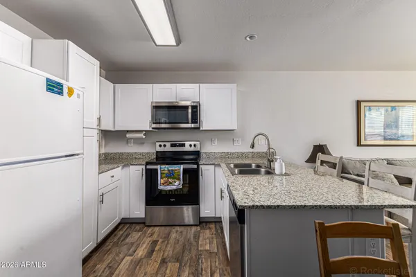 a kitchen with granite countertop a sink stove and refrigerator