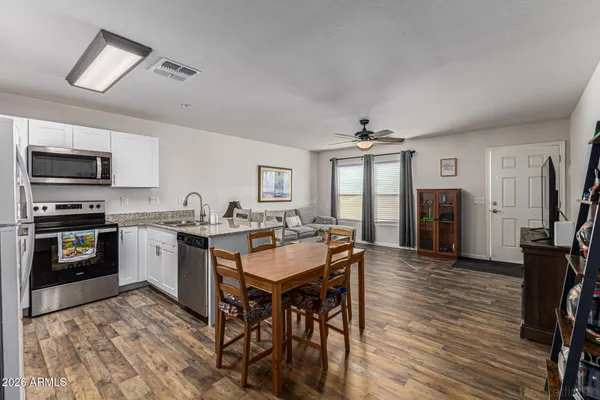 a kitchen with granite countertop stainless steel appliances a stove top oven a sink a dining table and chairs
