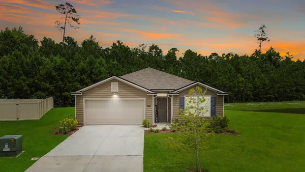 a front view of a house with a yard and trees